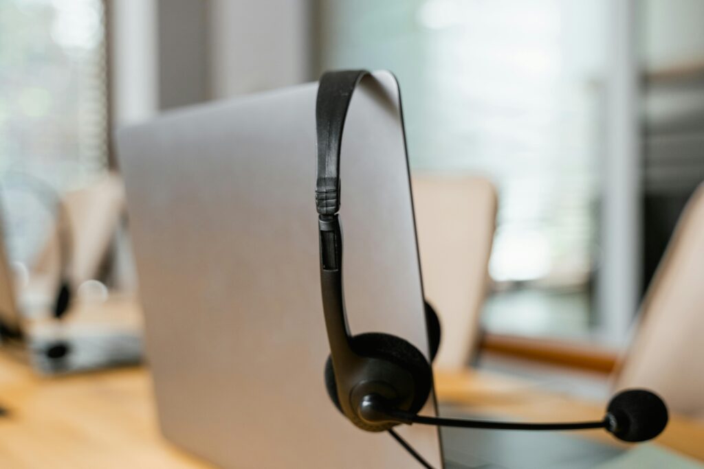 A headset hanging on a computer in a modern office setting for customer support.