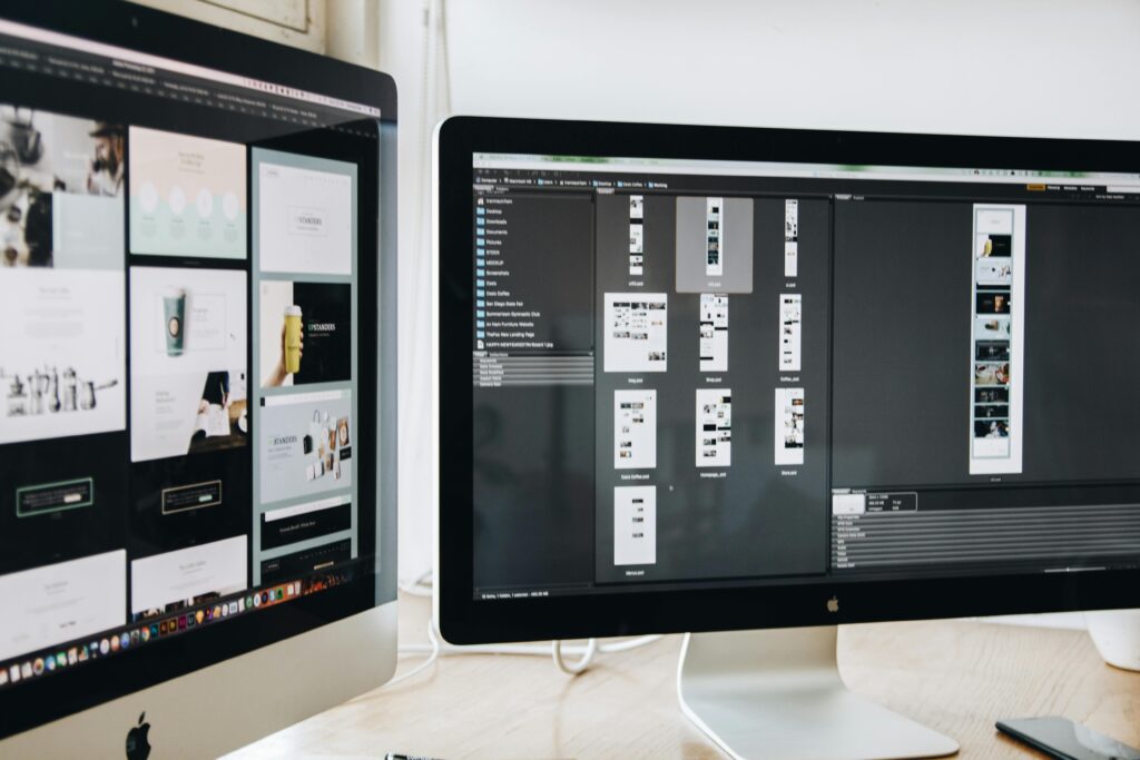 A modern workspace featuring dual computer monitors displaying web design projects, emphasizing technology and productivity.